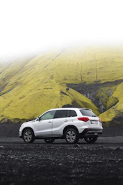 a white suv parked in front of a mountain