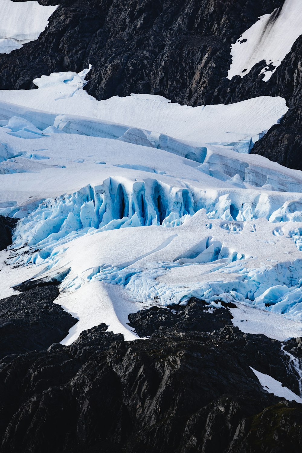 a large glacier with snow on the ground and mountains in the background