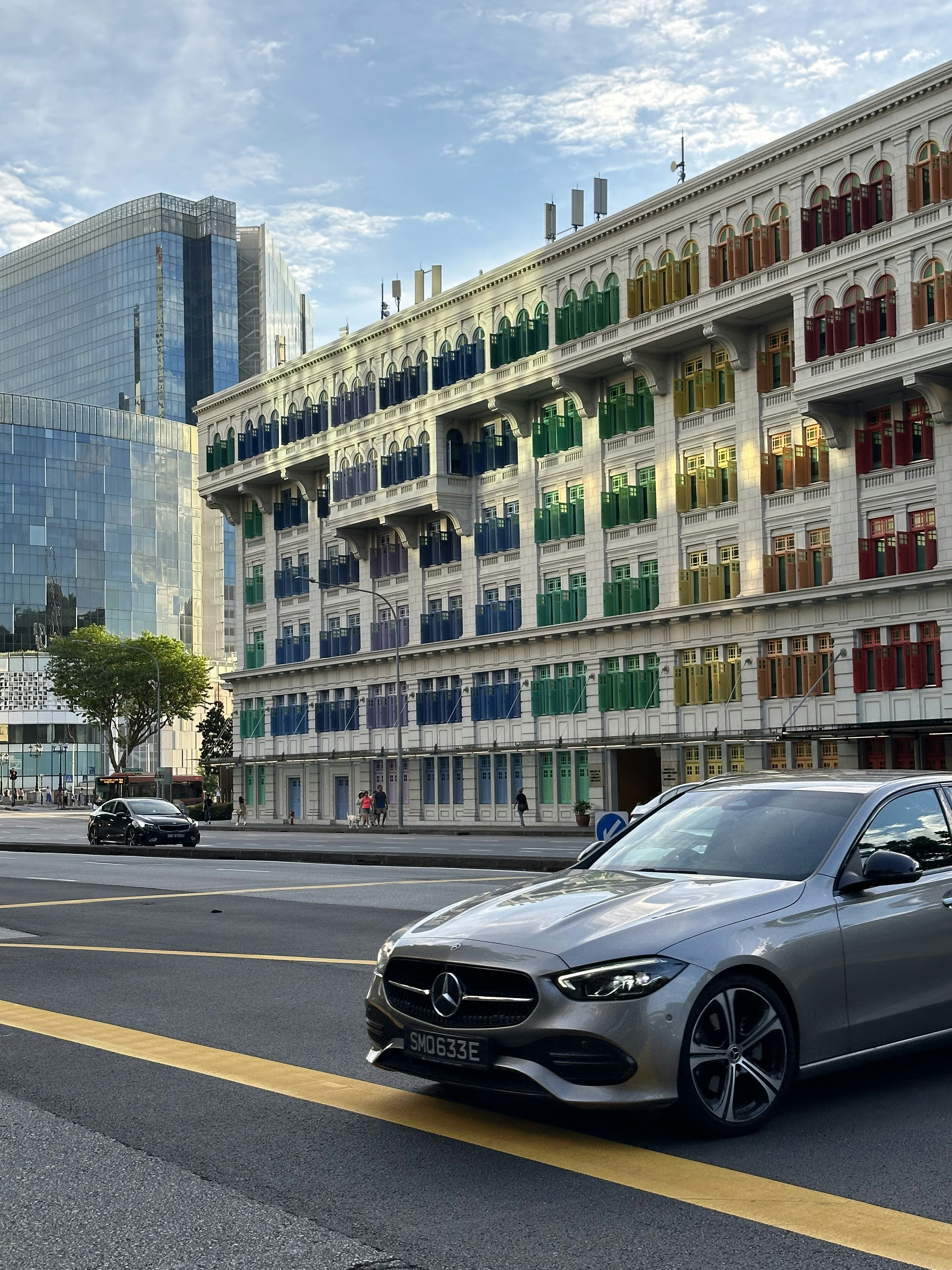 a silver car driving down a street next to tall buildings