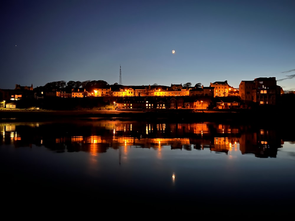 a night view of a city with a lake in front of it