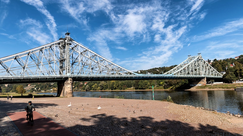 a man walking across a bridge over a river