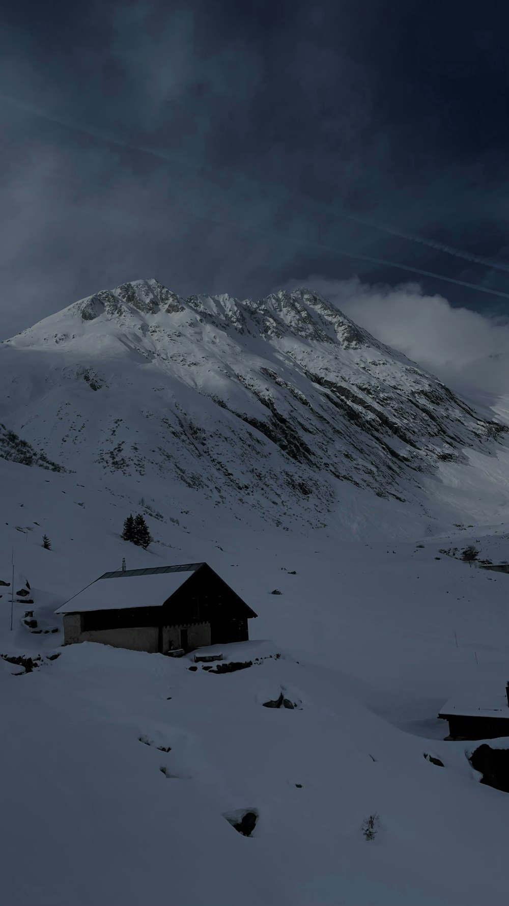 una montaña cubierta de nieve con una casa en primer plano