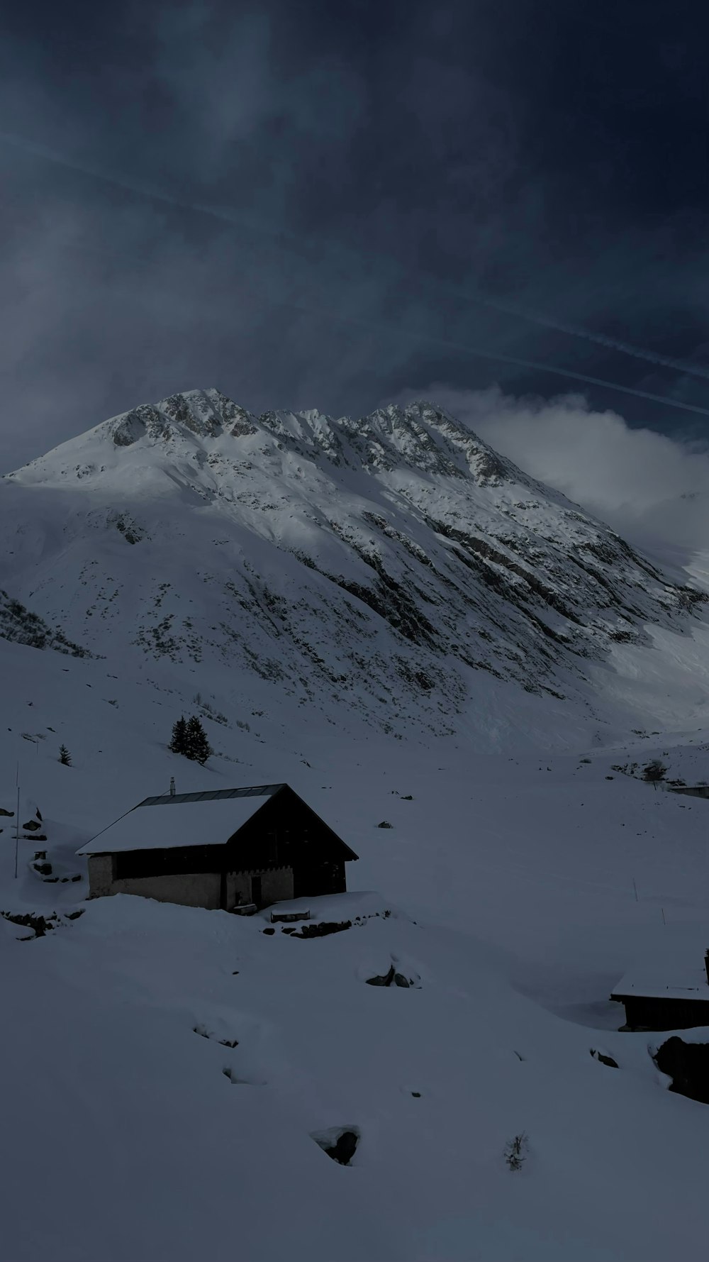 ein schneebedeckter Berg mit einem Haus im Vordergrund