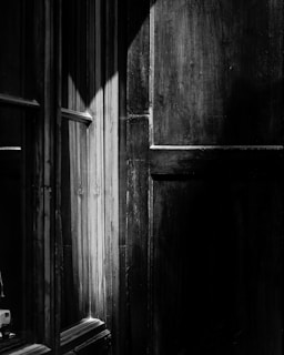 a black and white photo of a door and window