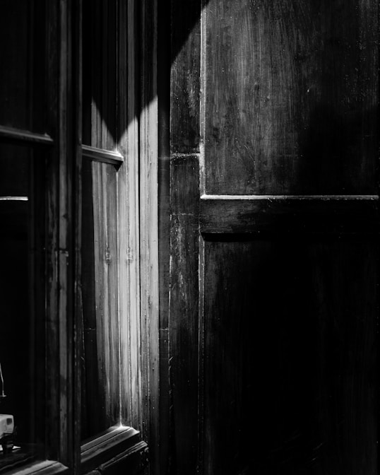 a black and white photo of a door and window
