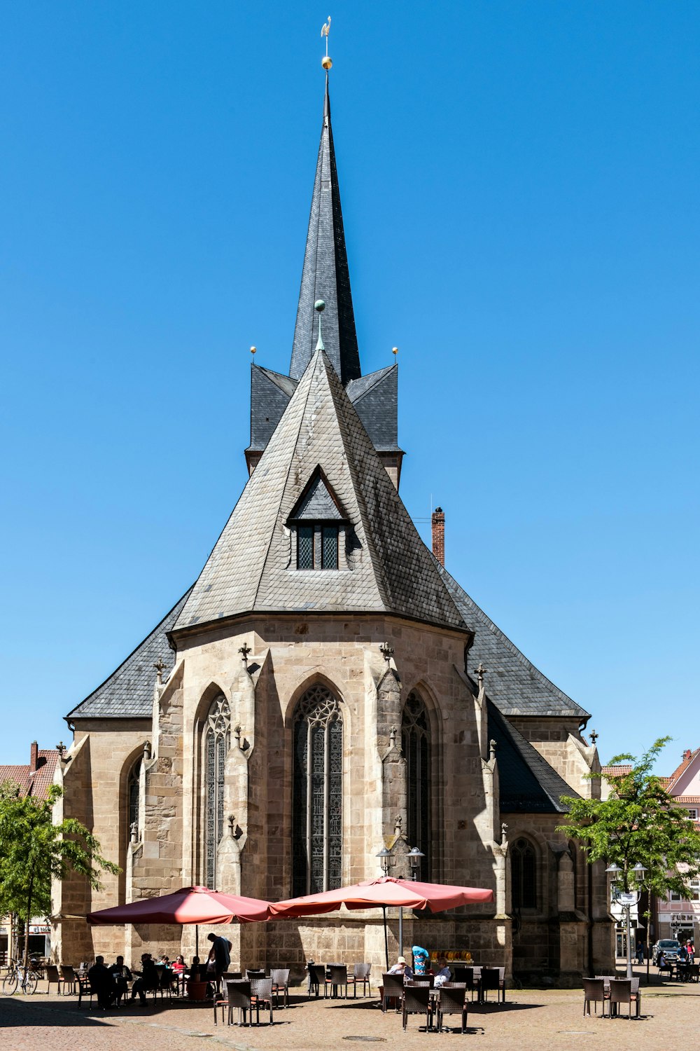 a church with a steeple and tables and umbrellas