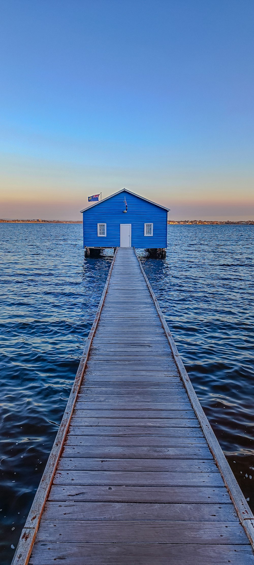 a blue house sitting on top of a wooden pier