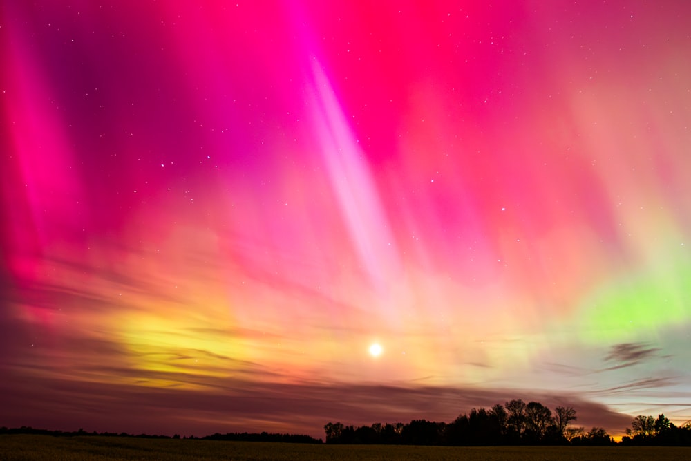 Um furo colorido da aurora está no céu acima de um campo