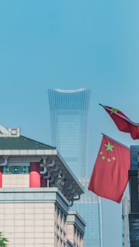 two flags flying next to each other in front of a building