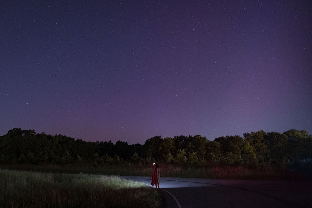 a person standing on the side of a road at night
