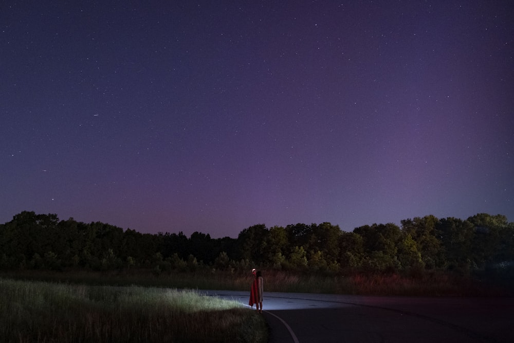 una persona parada al costado de una carretera por la noche