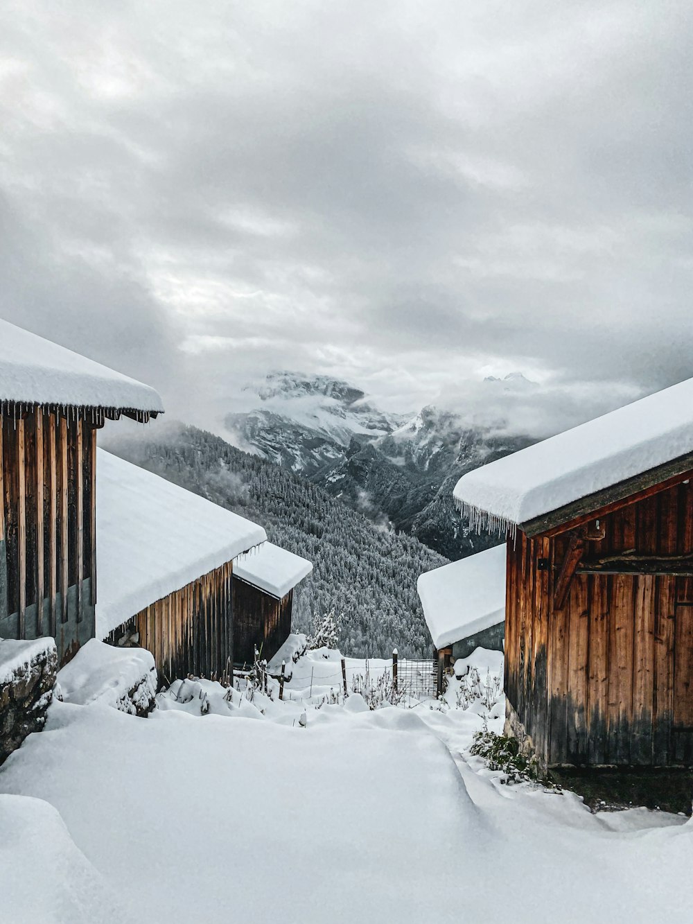 a couple of wooden buildings sitting on top of a snow covered slope