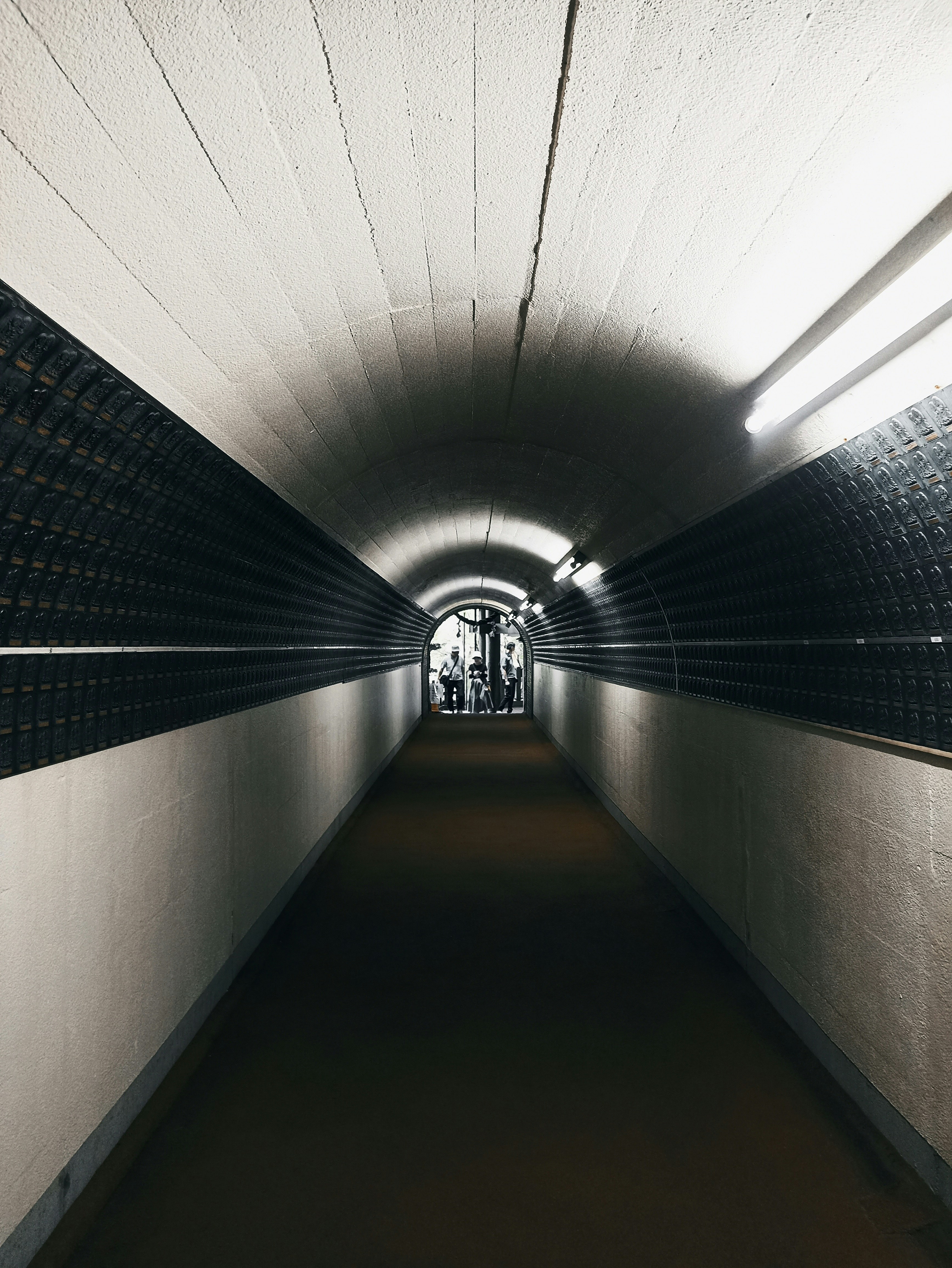 Well-lit underground tunnel with people entering from the other side – a dynamic urban passageway co