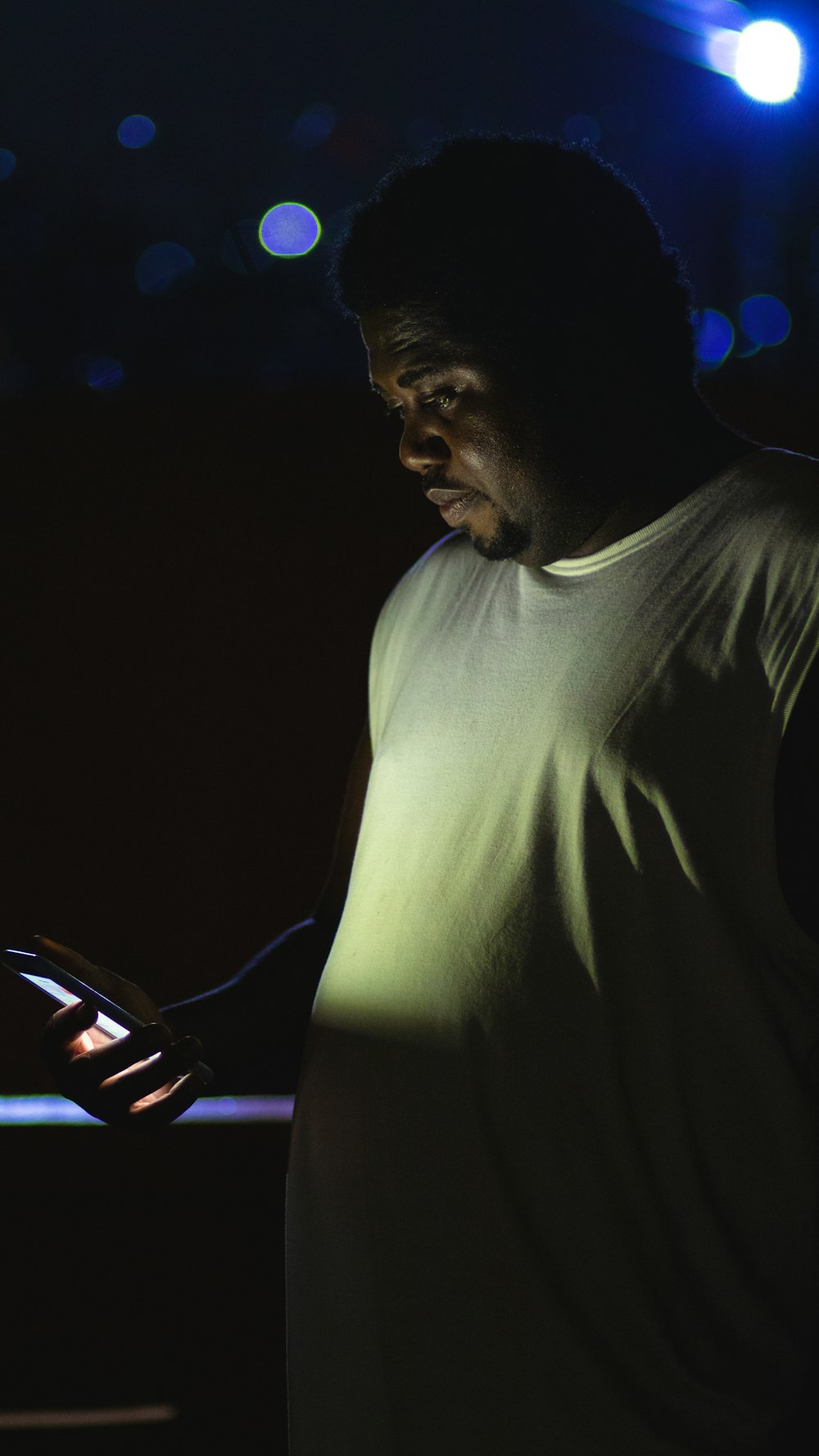 a man standing in the dark holding a cell phone