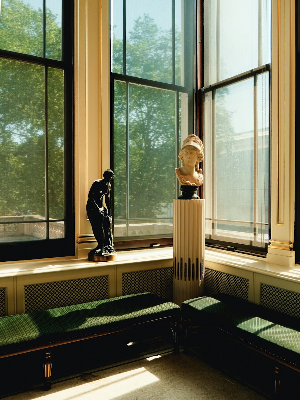 a statue of a man sitting on a bench next to a window