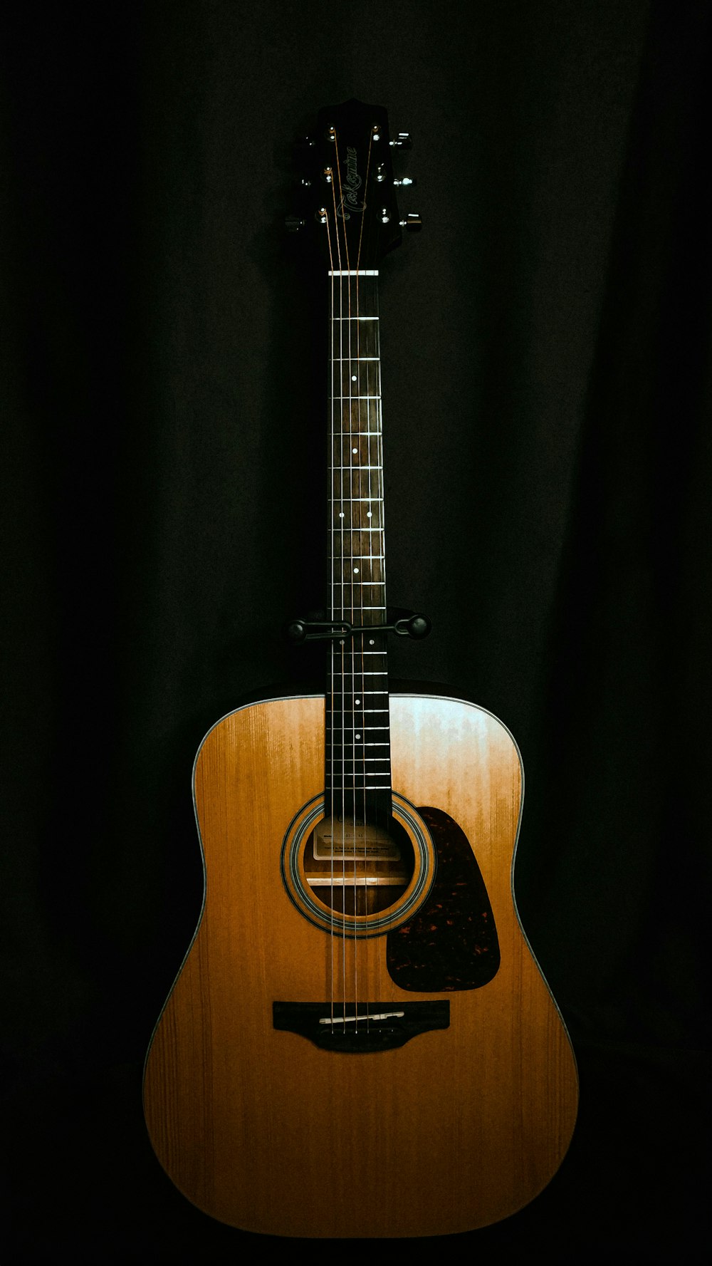 an acoustic guitar sitting on a black background