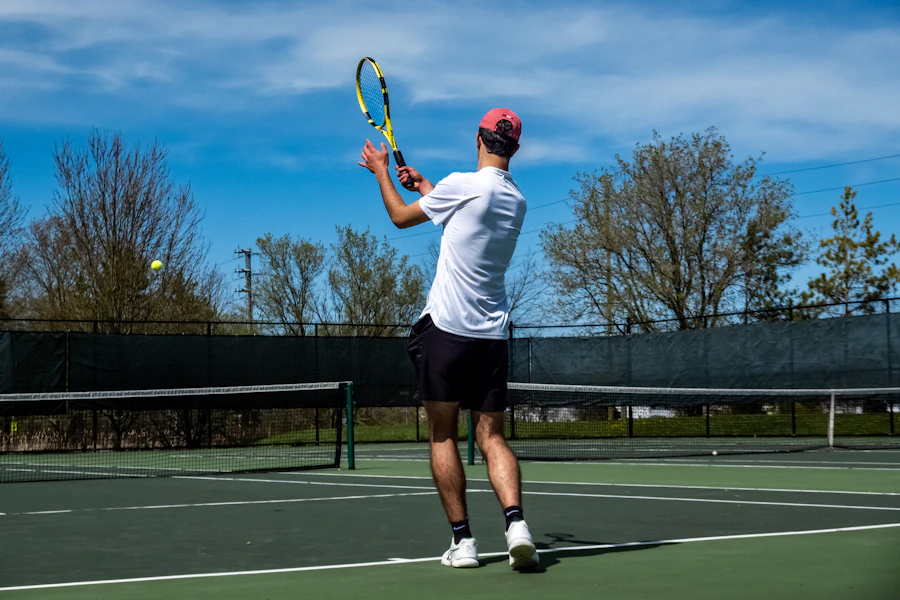 Player standing on a tennis court holding a racket, gear in hand