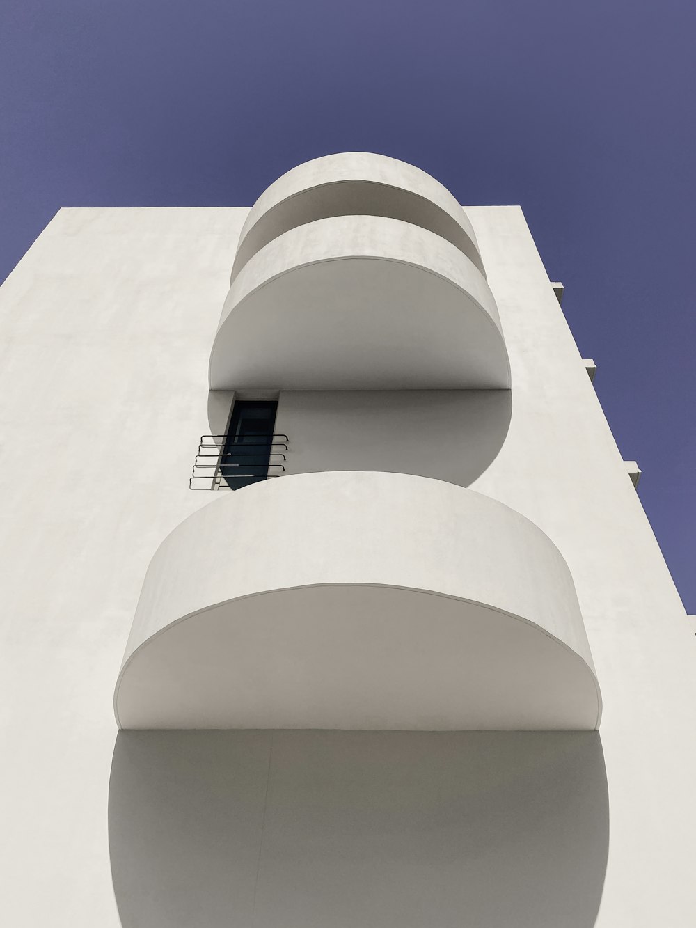 a tall white building with balconies and a window