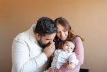 a man and woman holding a baby in their arms