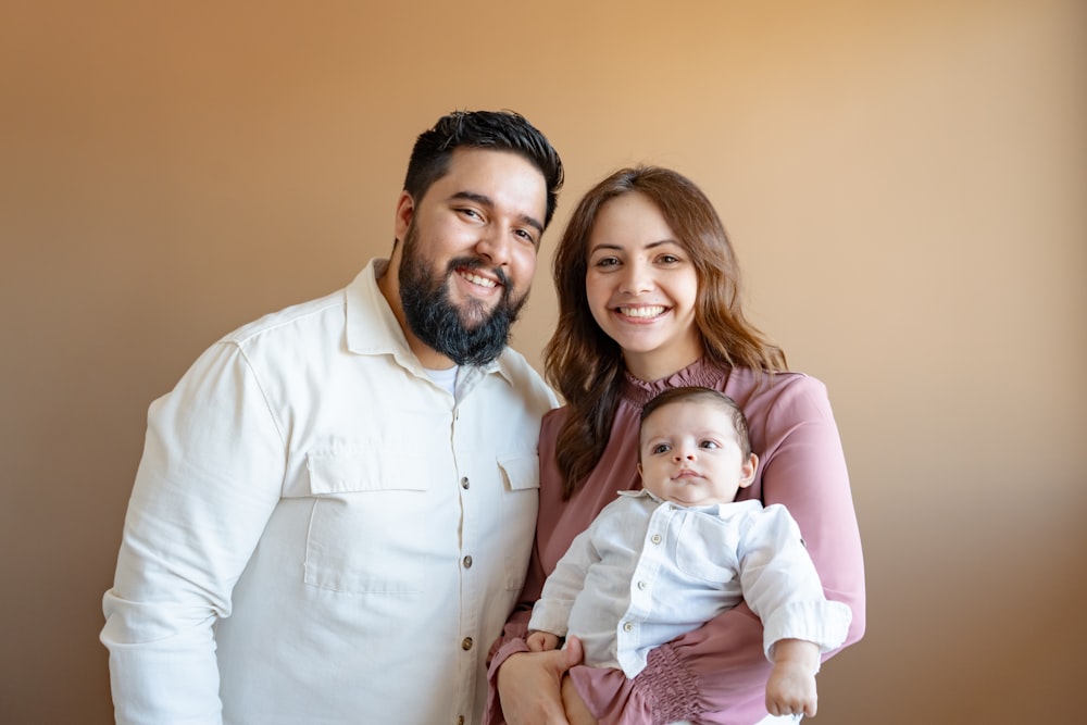 a man and woman pose for a picture with a baby