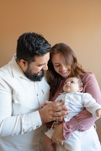 a man and woman holding a baby in their arms