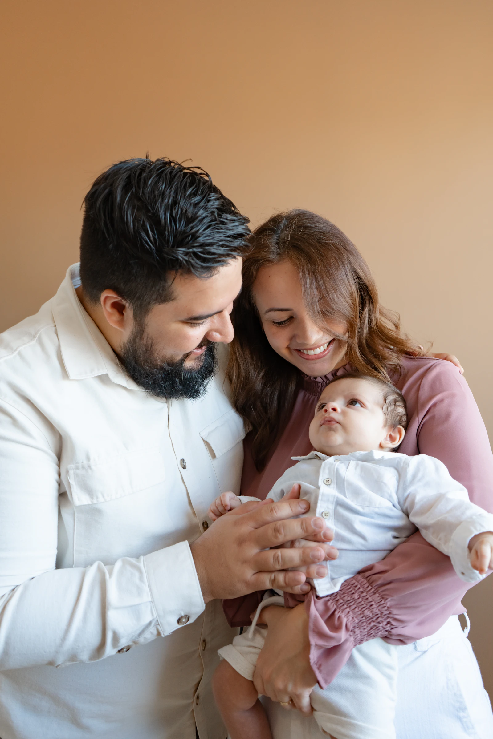 Pais sorrindo com o bebê recém-nascido no colo