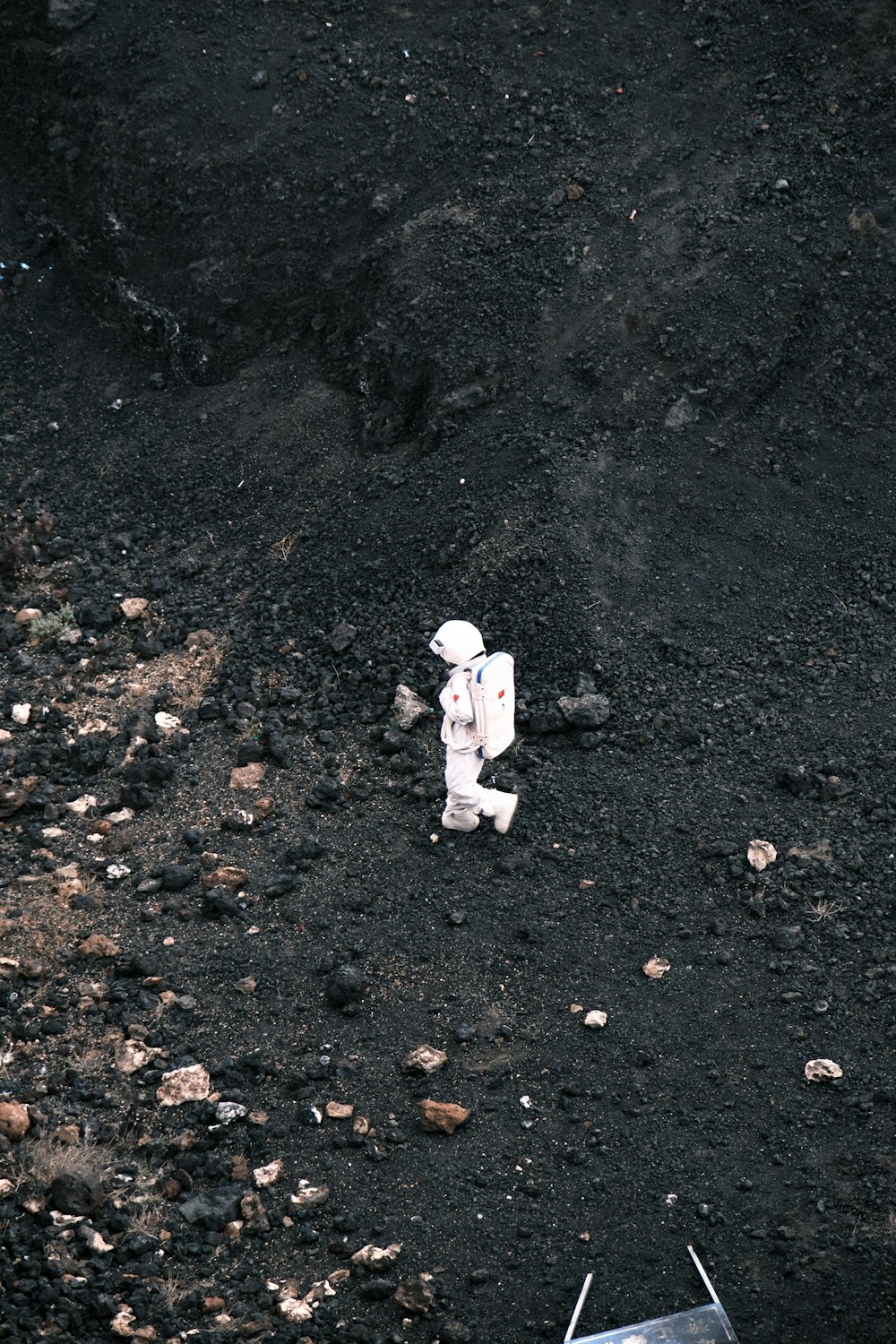 a small toy astronaut walking across a dirt field