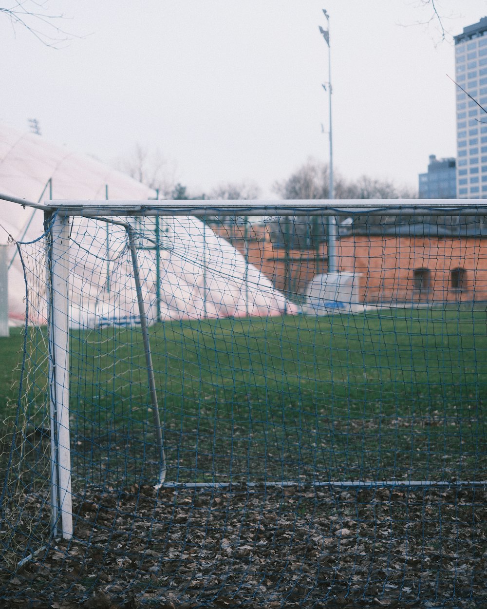 a soccer goal in a field with a building in the background