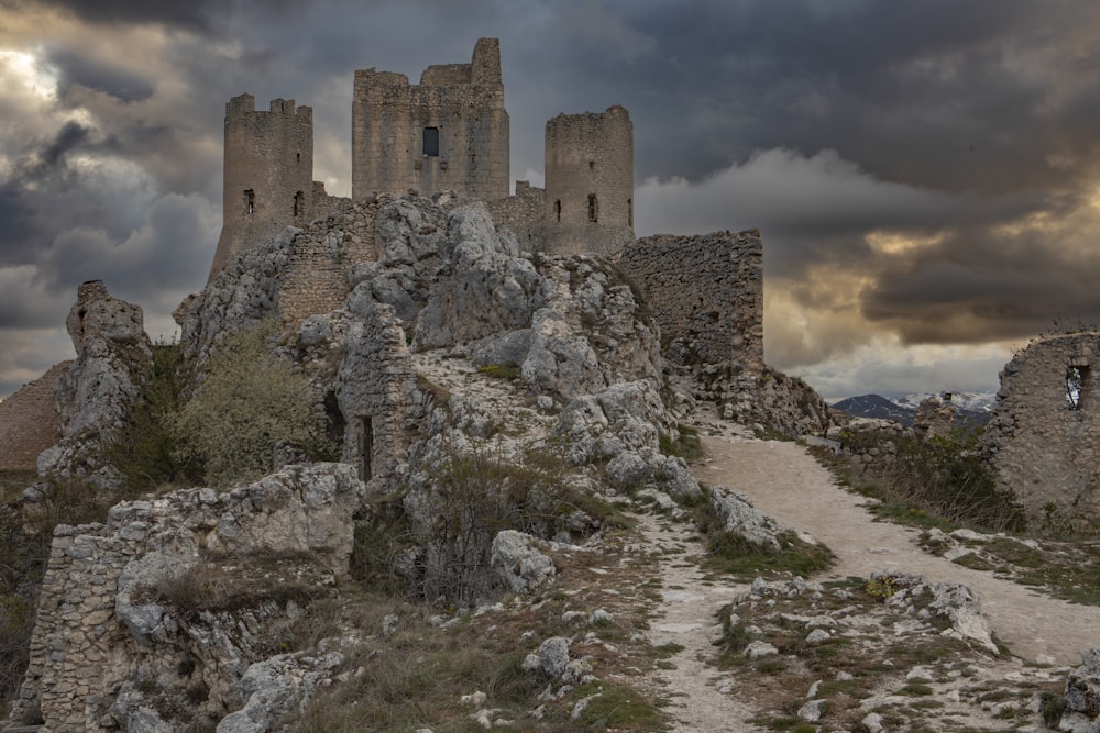 a stone castle on a rocky hill under a cloudy sky