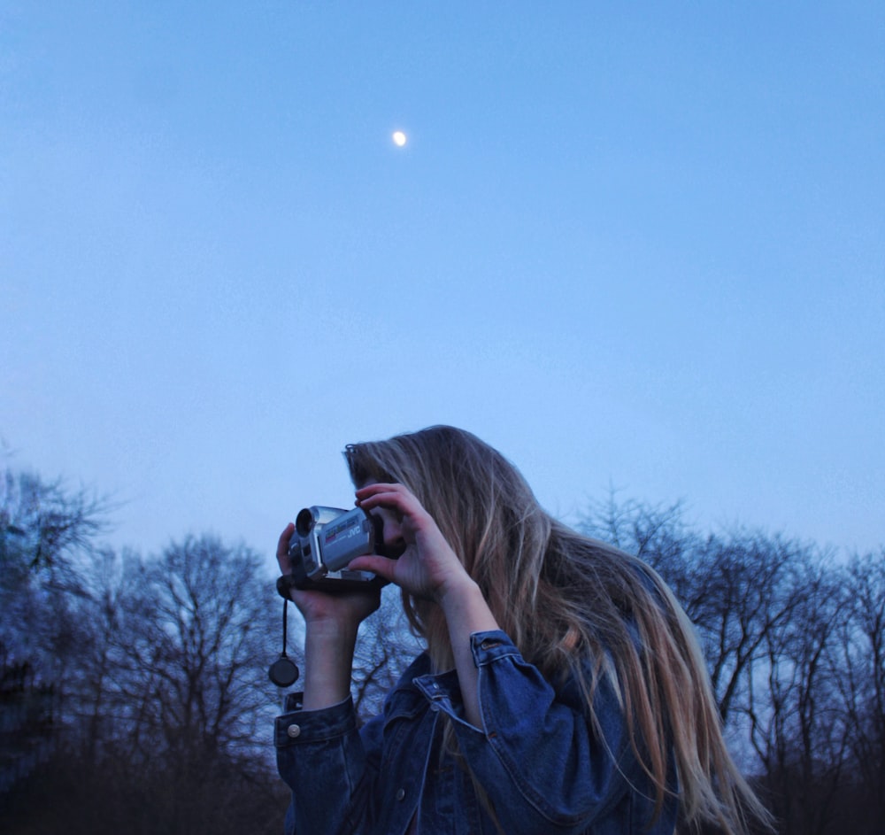 a woman taking a picture of the moon with a camera