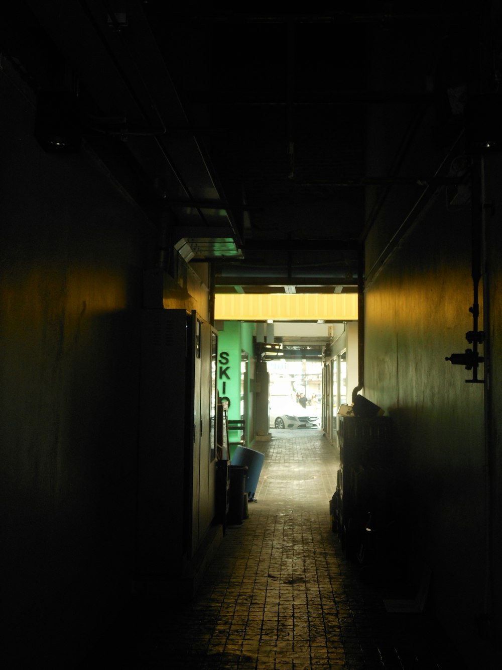 a dark hallway with a tiled floor and green walls