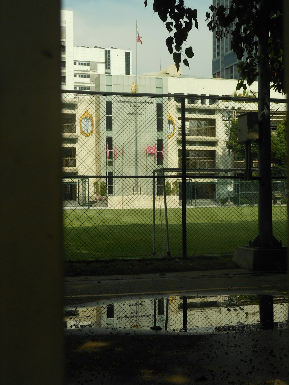 a grassy field behind a fence with a building in the background