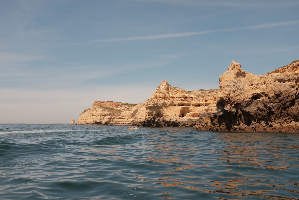 a body of water next to a rocky cliff