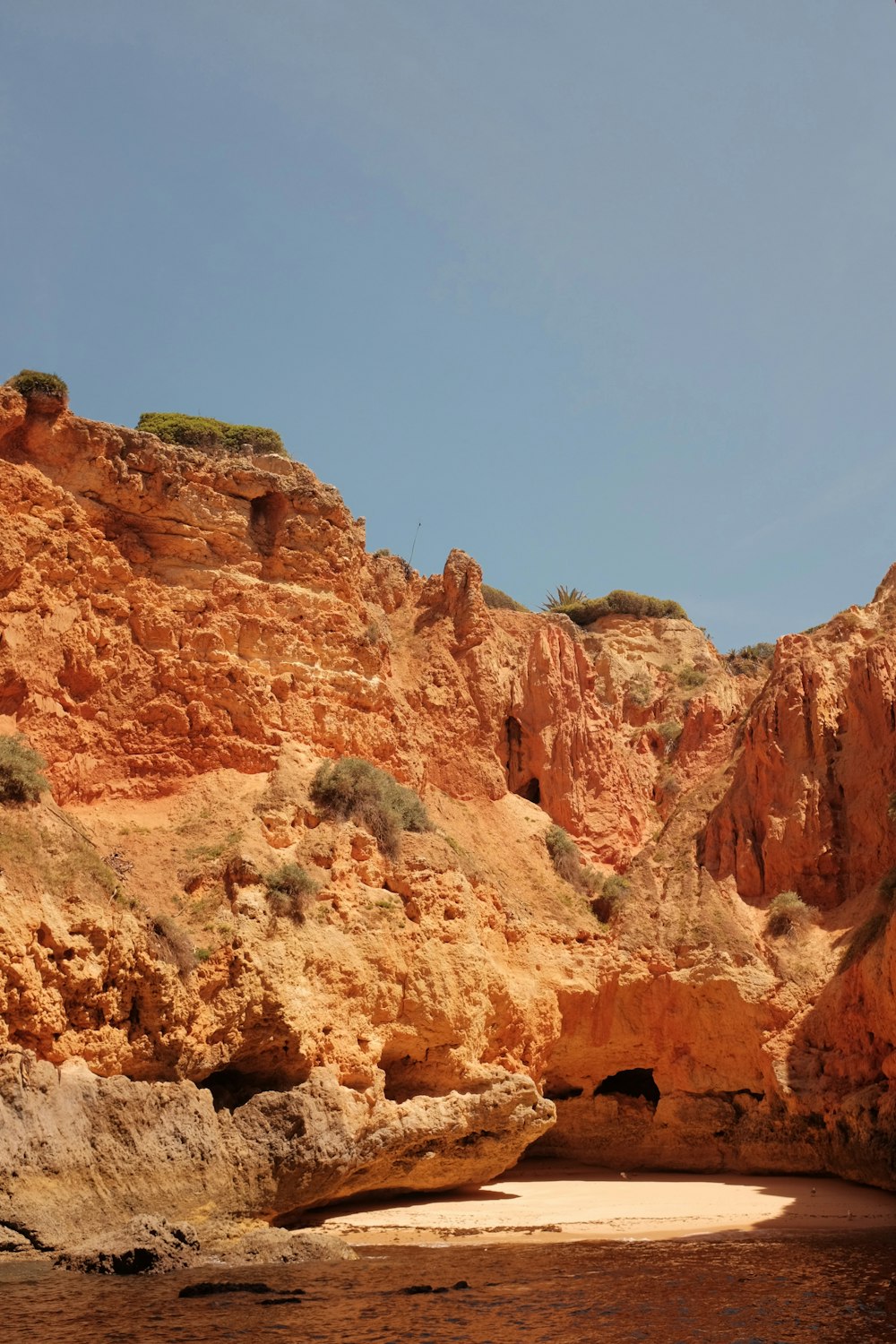 a rocky cliff with a body of water in front of it