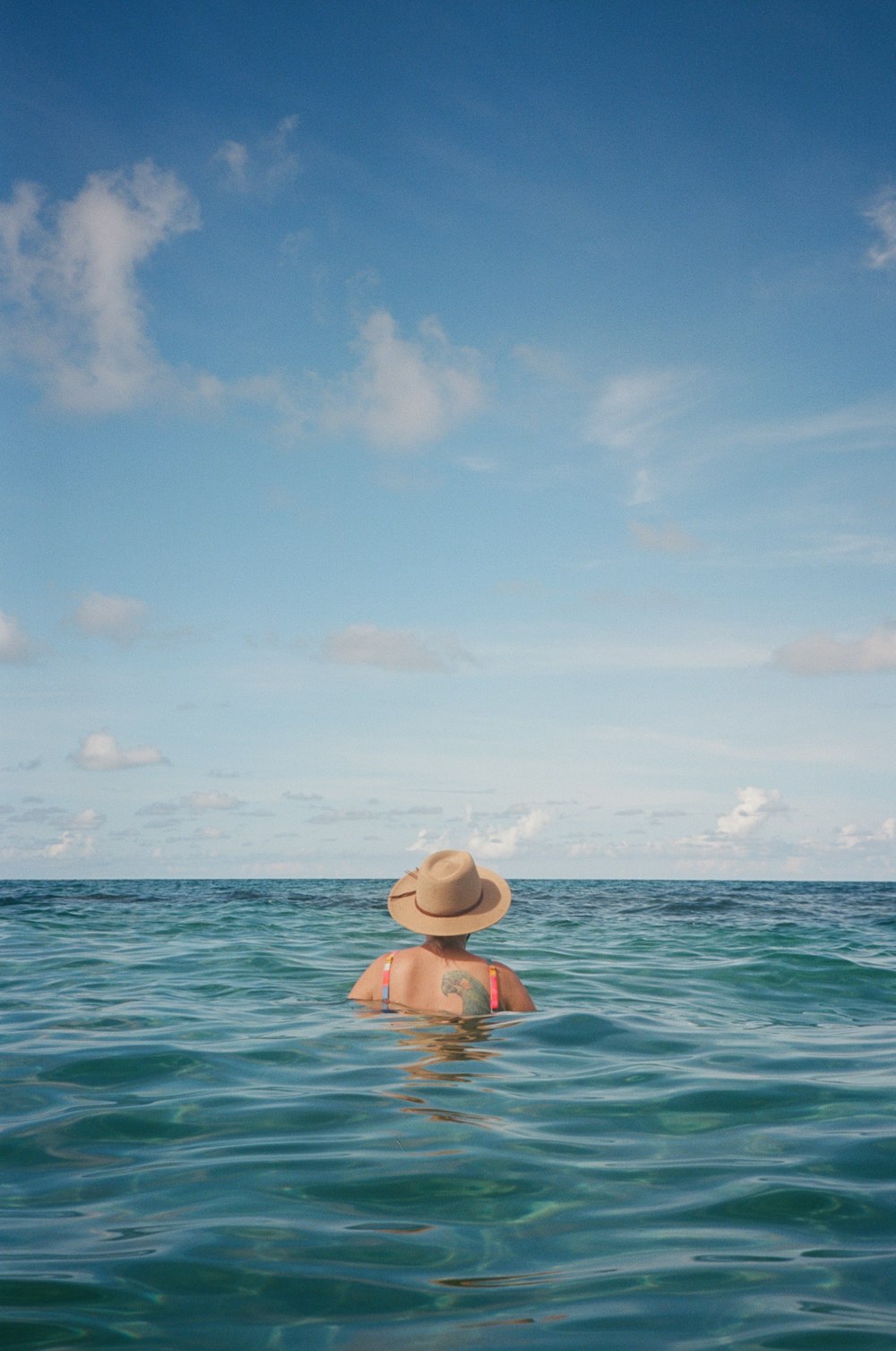 a woman in a bikini and hat in the ocean