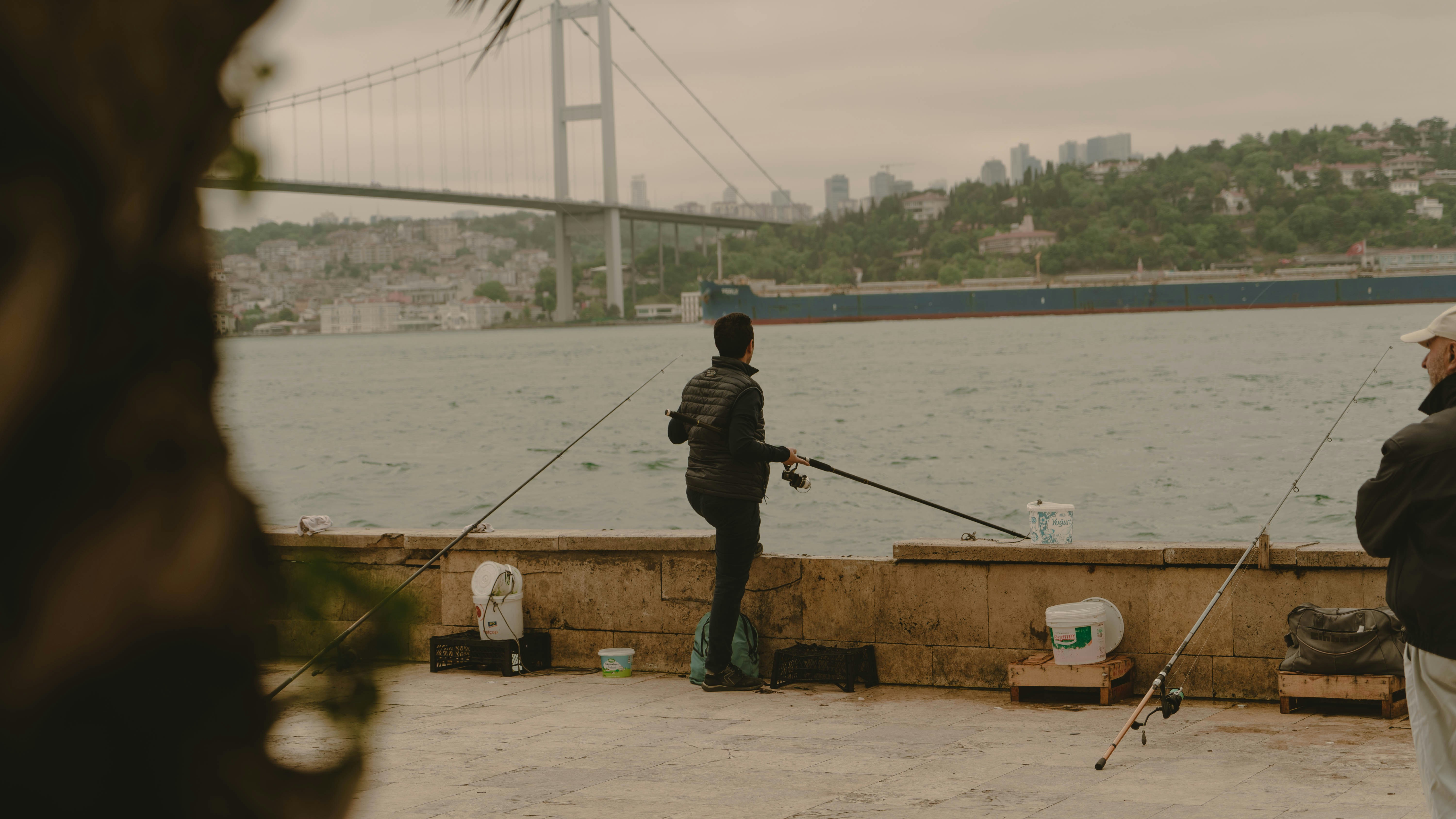 a couple of people standing on a pier next to a body of water