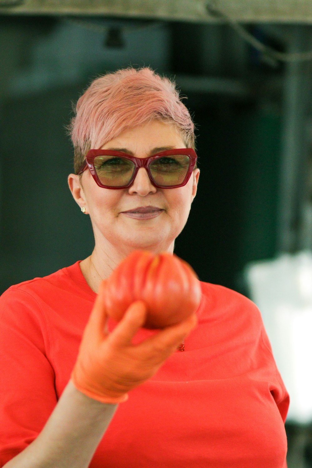 a woman in a red shirt holding a tomato