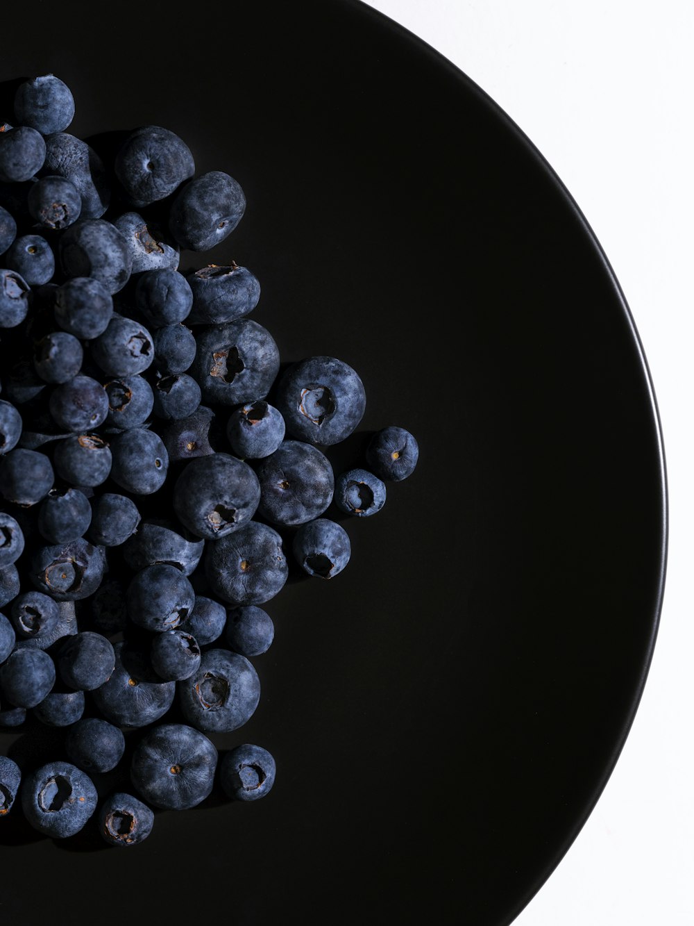 a black plate topped with blueberries on top of a table