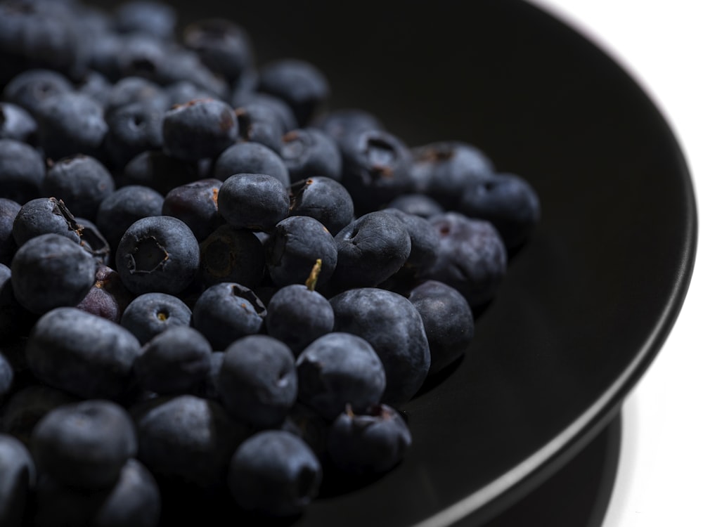 a black bowl filled with blueberries on top of a table