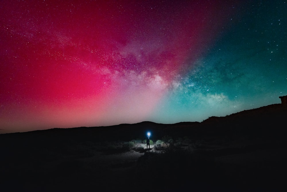 a person standing in the middle of a field under a night sky filled with stars