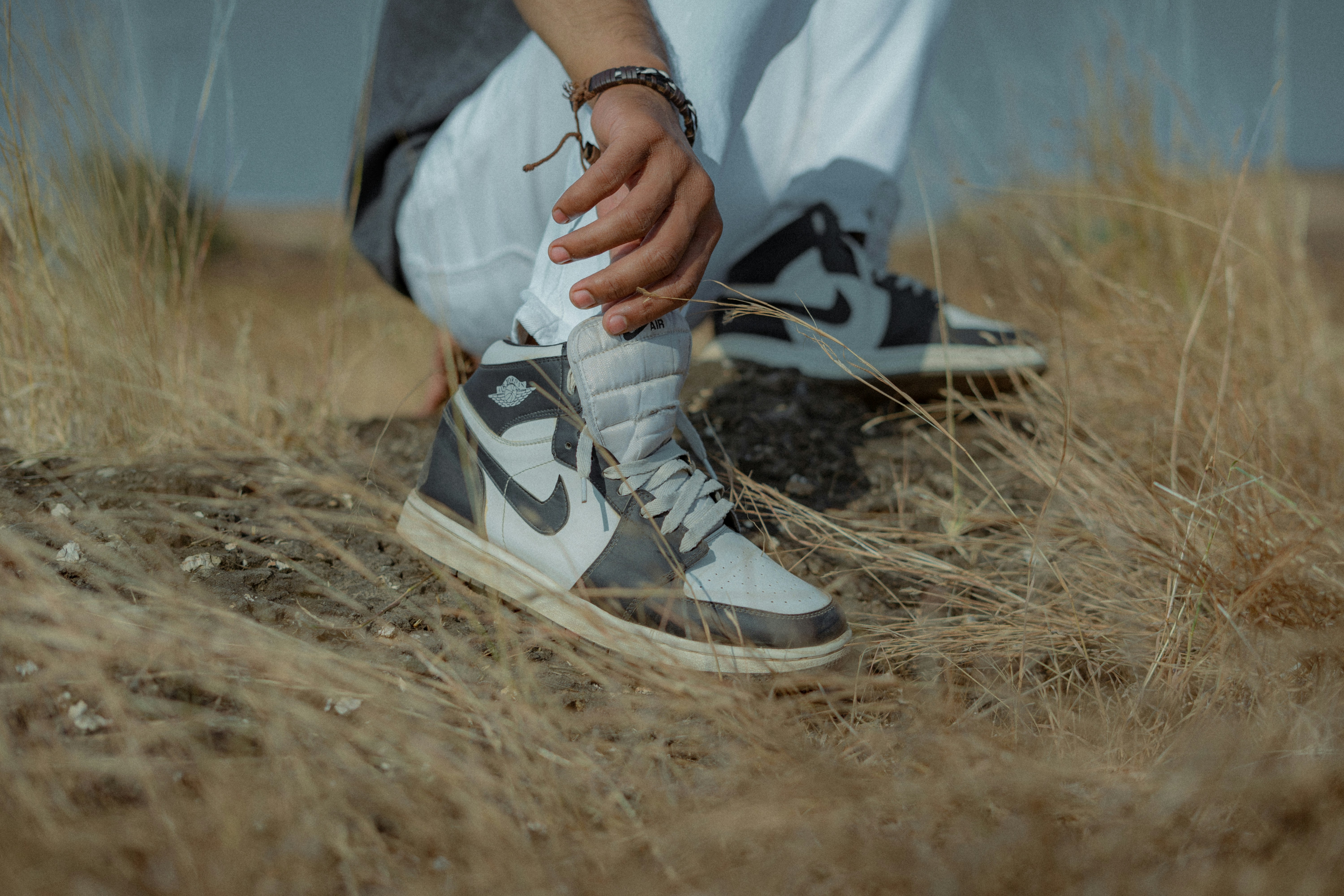 A person with their foot on a pair of sneakers