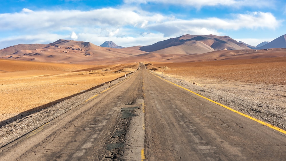 a road in the middle of a desert with mountains in the background