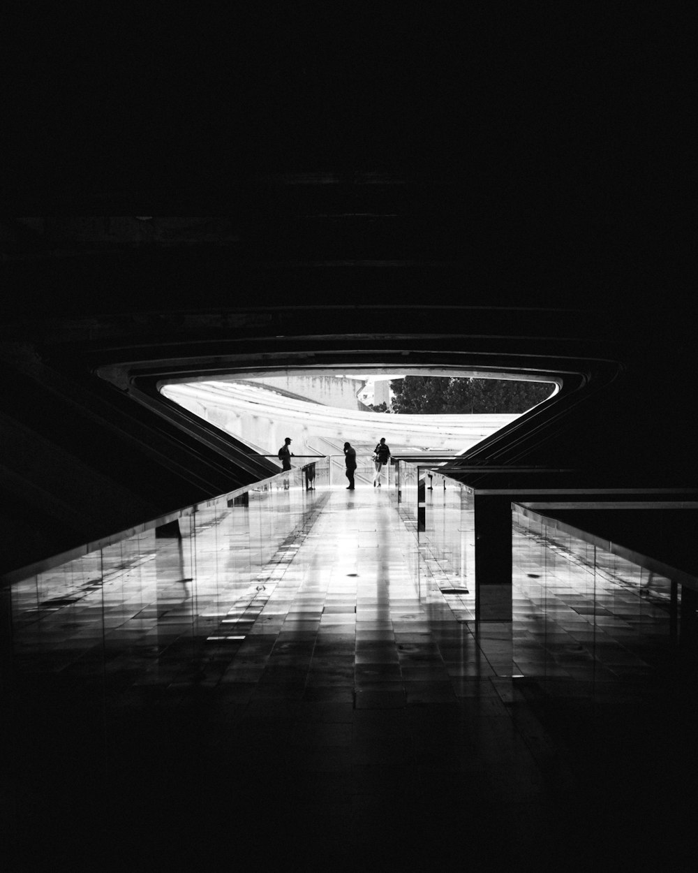 a black and white photo of people walking through a tunnel
