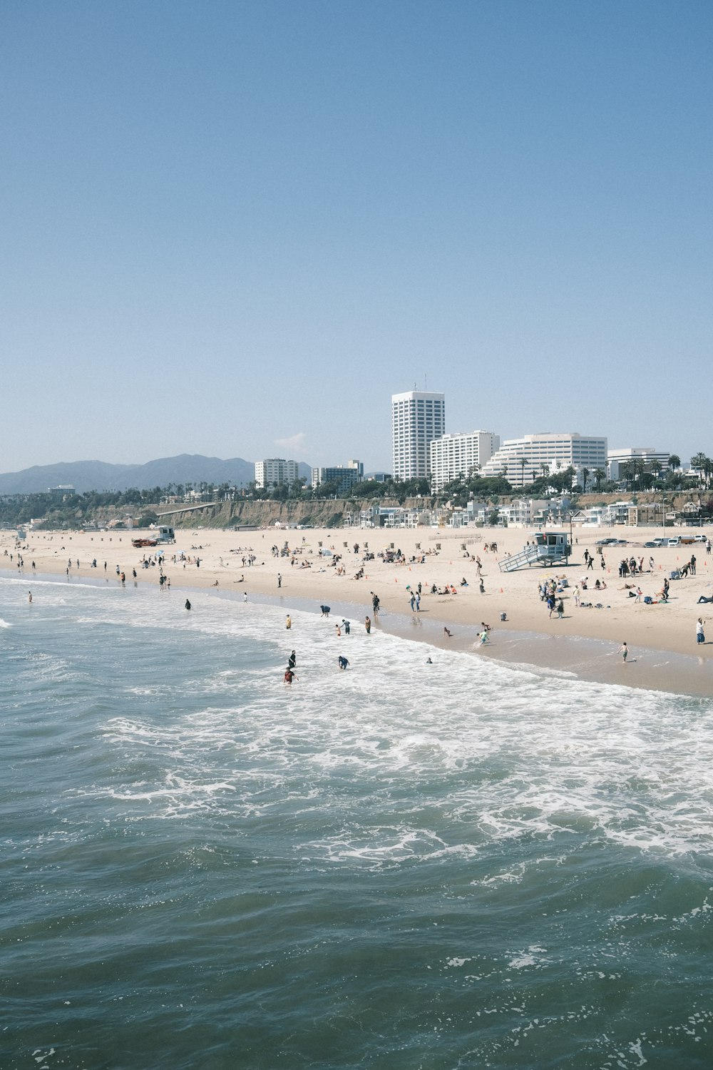 a crowded beach with people on it and buildings in the background