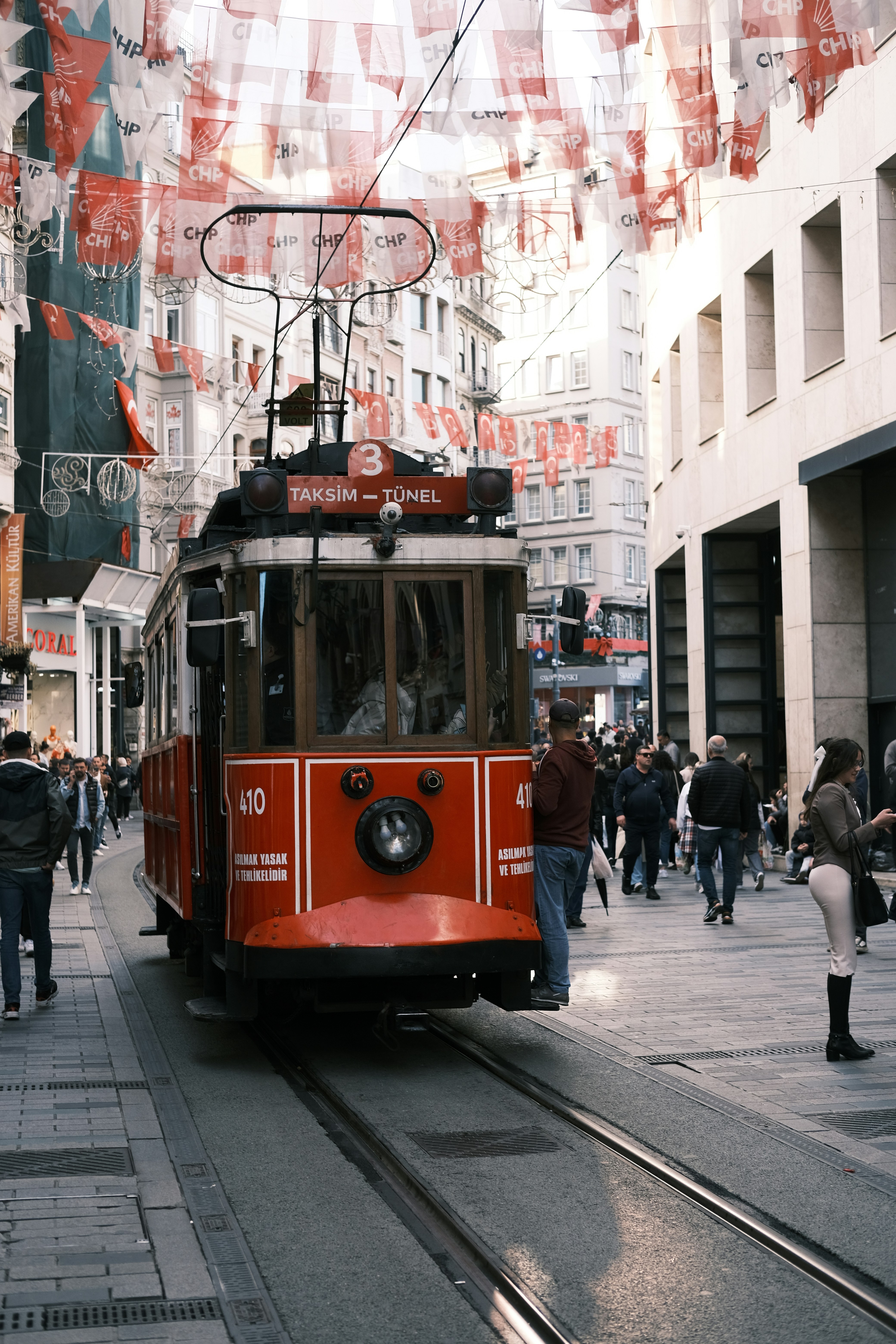a red trolley car traveling down a street next to tall buildings
