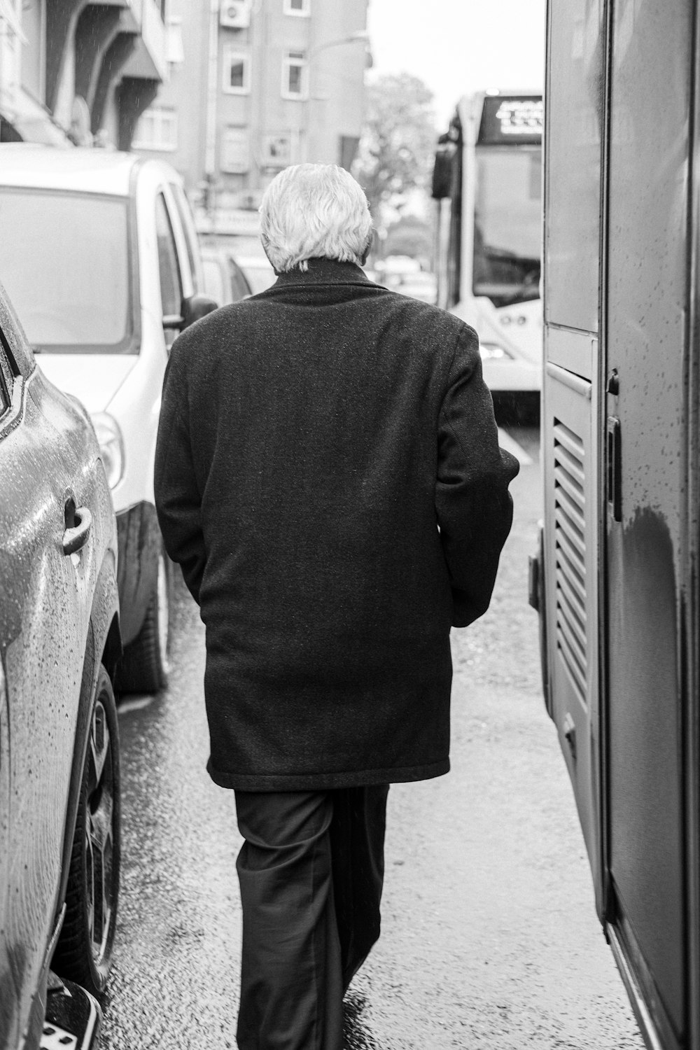 a man walking down a street next to parked cars