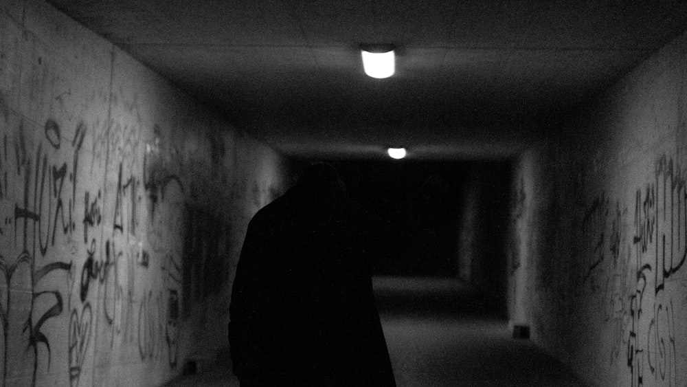a person in a dark tunnel with graffiti on the walls