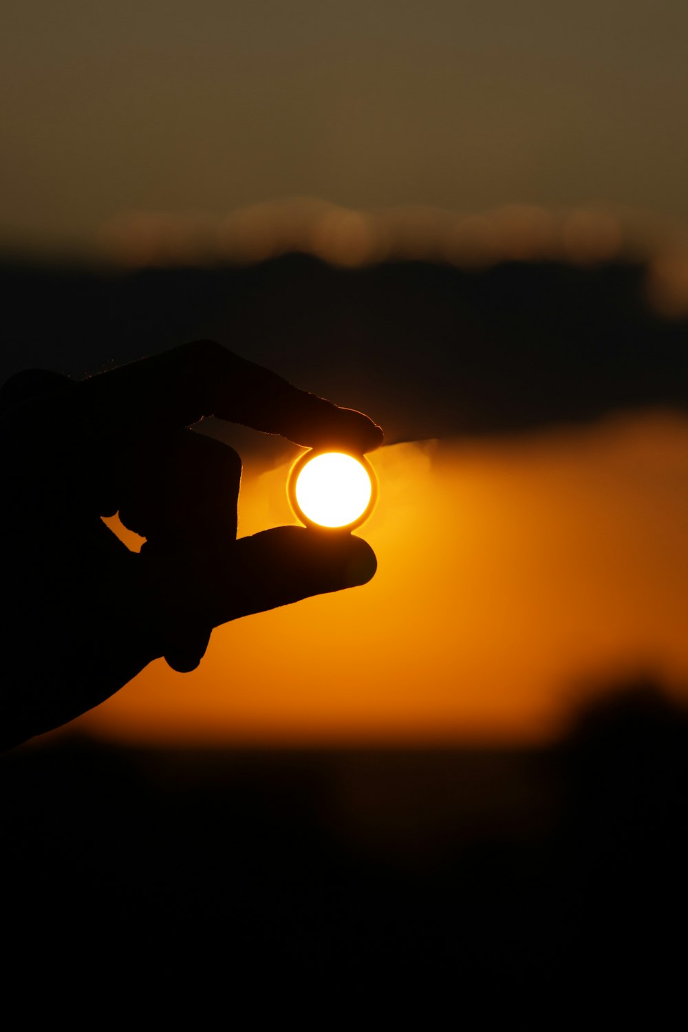the sun is setting behind a silhouette of a person's hand