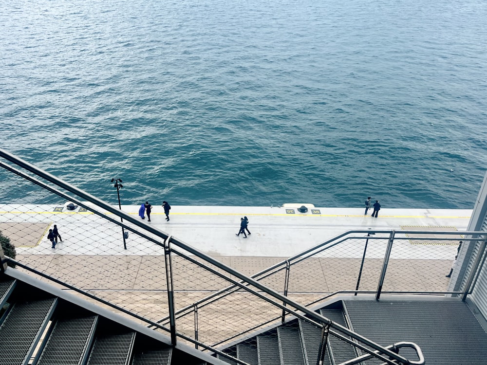 a group of people walking down a flight of stairs next to the ocean