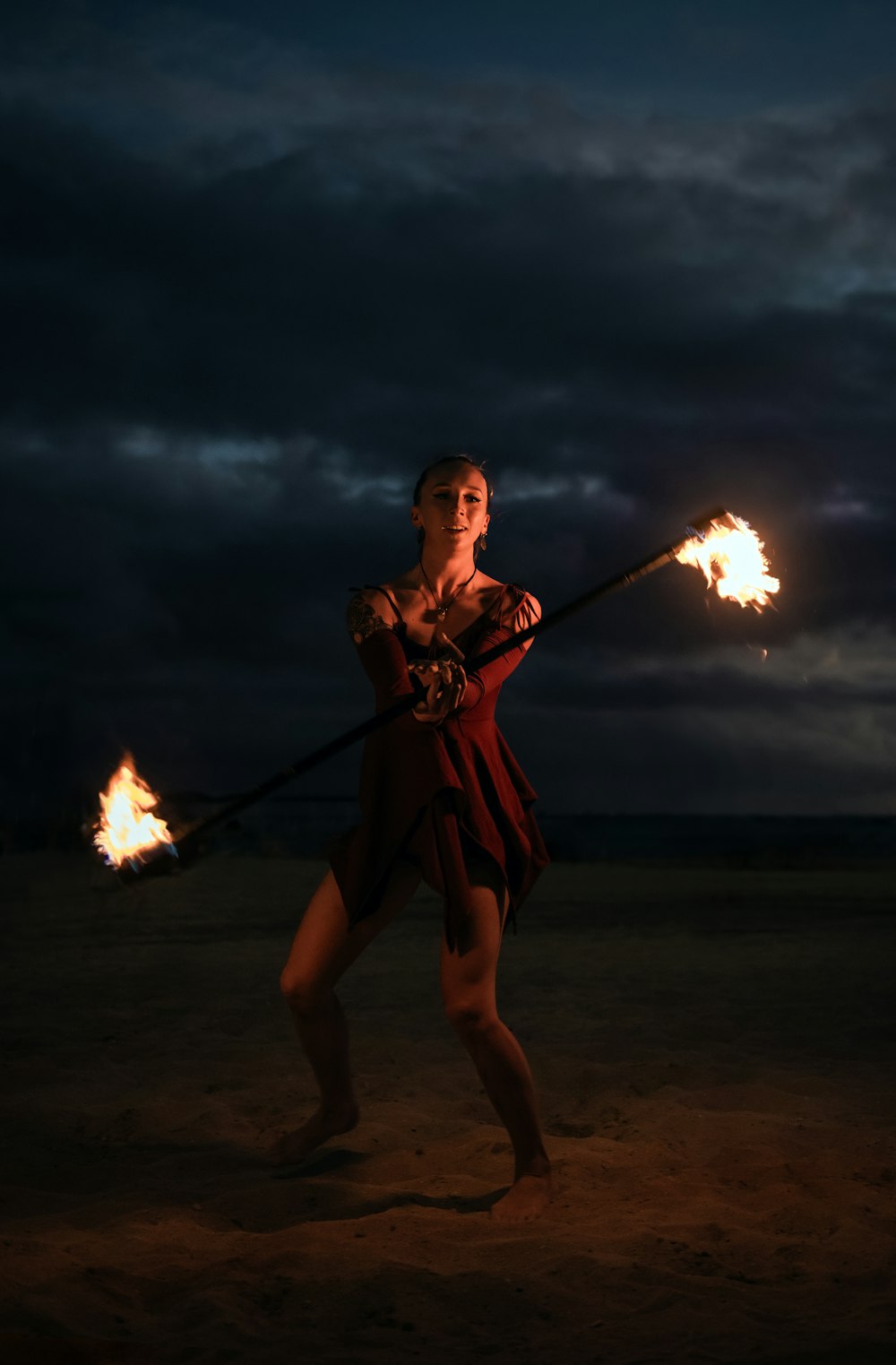 a woman in a red dress holding two torches